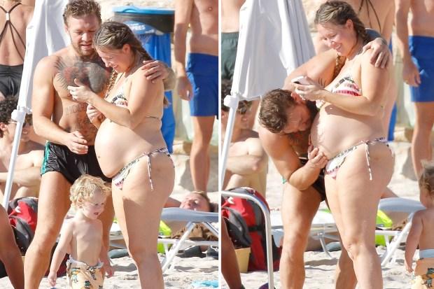 康纳·麦格雷戈 (Conor McGregor) 与怀孕的未婚妻迪伊·德夫林 (Dee Devlin) 在法国海滩上携带 PDA，并在她的肚子上温柔地亲吻